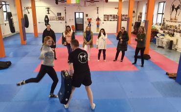 Woman kicking kickboxing pad held by Instructor Paul